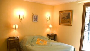 Una stanza con un letto, due comodini con lampade, un quadro appeso al muro e una porta con vista.