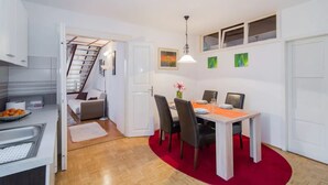 En kompakt bolig med tekøkken, spiseplads og trappe op til et opholdsrum.