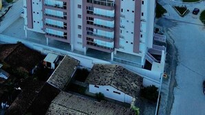 Um hotel de vários andares com telhado plano, rodeado por edifícios residenciais e uma costa.