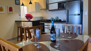 Uma cozinha moderna com eletrodomésticos de aço inoxidável, cadeiras de madeira e uma mesa de jantar posta para dois.