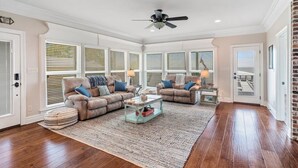 Un salon spacieux avec deux canapés beige, une table basse et un ventilateur de plafond.