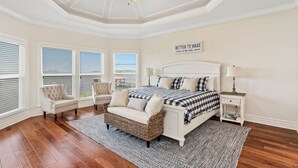 Une chambre à coucher avec un grand lit, deux fauteuils, une table de chevet et un ventilateur de plafond.