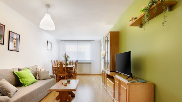 A living room with a sofa, coffee table, TV stand, and a dining area with chairs and a table. - Beautiful apartment, ideal for families in the Aragonese Pyrenees. (Sabiñánigo)