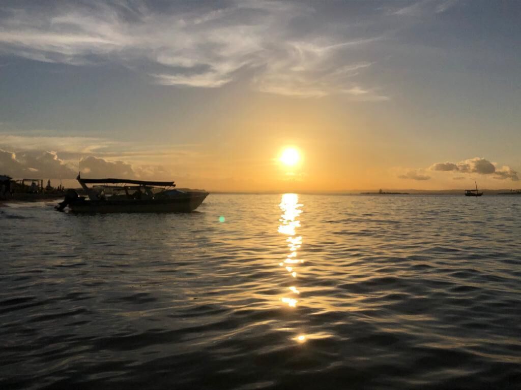 A boat on calm water reflecting the sunset.