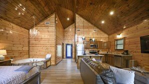 Interior de una cabaña de madera con un dormitorio, sala de estar y cocina.