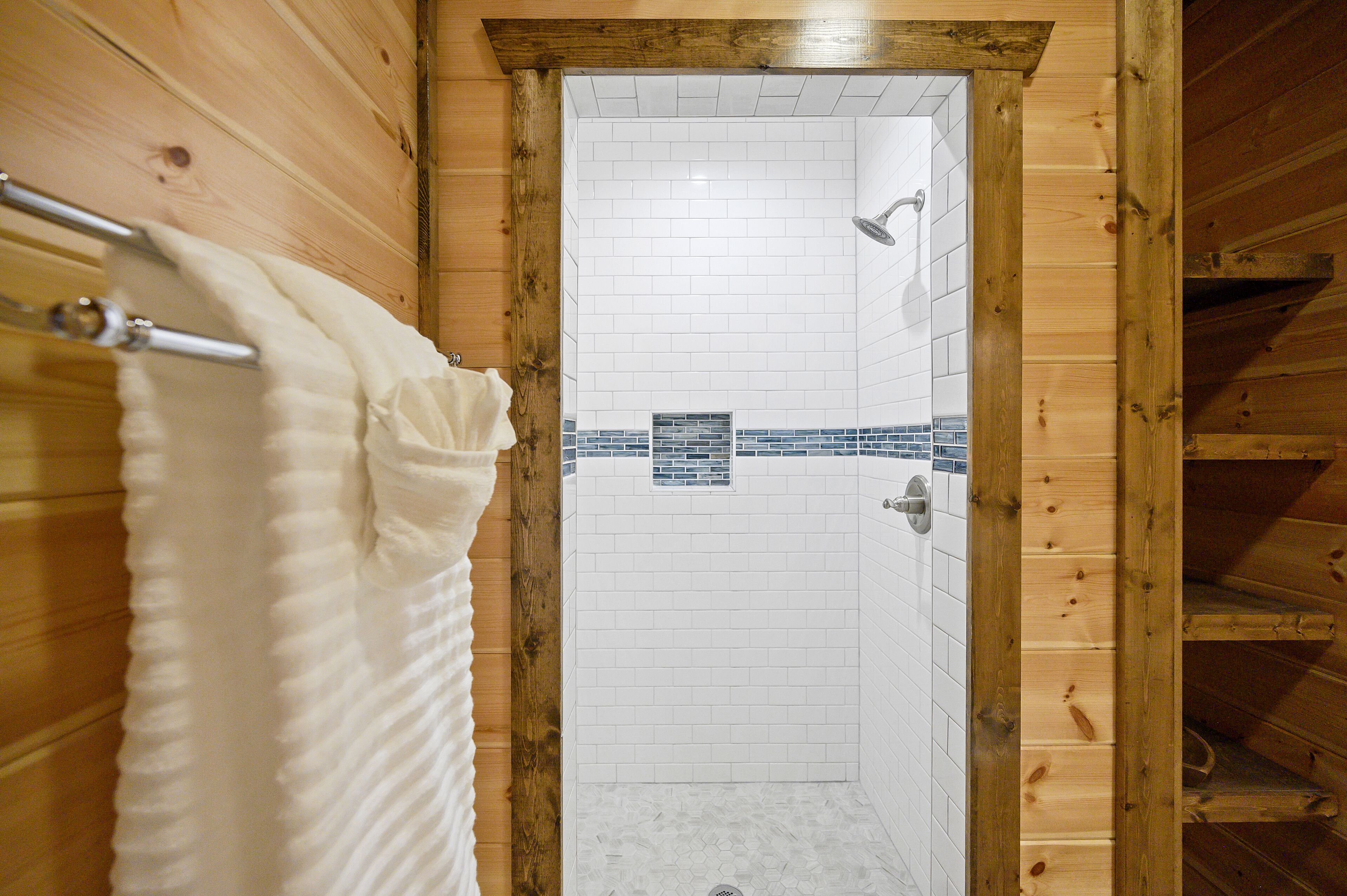 Interior de madera con zona de ducha, azulejos blancos y un detalle decorativo en azul.