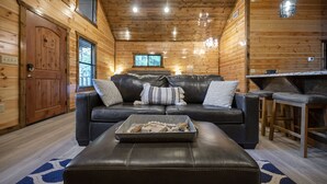 Interior acogedor de una cabaña con detalles de madera, un sofá de cuero y una zona de comedor.