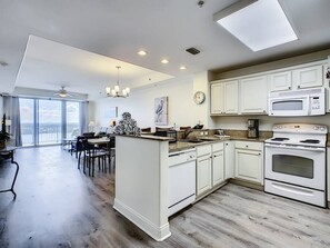 Une cuisine moderne avec des meubles blancs, un four encastré et un four à micro-ondes.