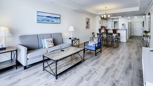 Ein modernes Wohnzimmer mit grauem Sofa, einem Couchtisch und einem Essbereich mit Stühlen und Tisch.