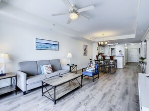 Un salon moderne avec un canapé gris, une table basse et un coin repas comprenant des chaises et une table.