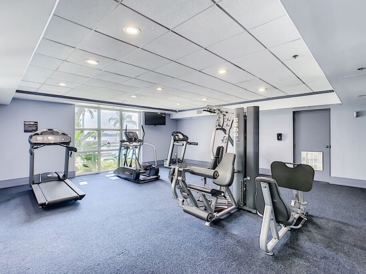 Un gimnasio moderno con cintas de correr, elípticas y bancos de pesas.