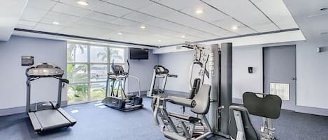 Un gimnasio moderno con cintas de correr, elípticas y bancos de pesas.