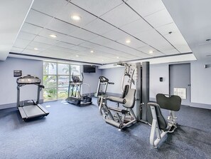A modern gym with treadmills, elliptical machines, and weight benches.