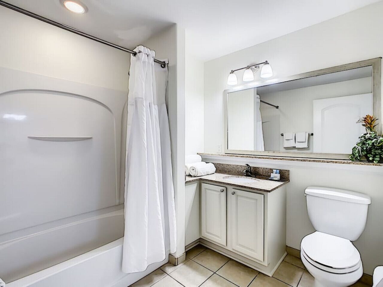 Ein Badezimmer mit Dusche, Toilette, Waschbecken und Spiegel.