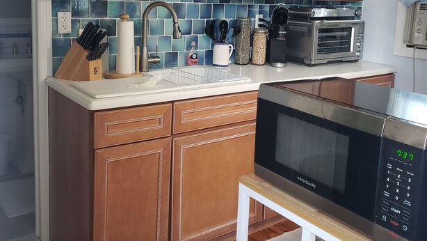 Una cocina con armarios de madera, un microondas, un horno tostador y un lavamanos.