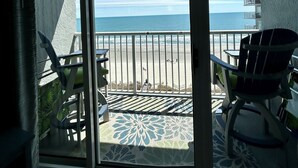 Un balcón con vista a la playa y al océano, con dos sillas y una mesa.