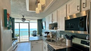 Cocina moderna con una isla grande, electrodomésticos de acero inoxidable y vistas al exterior.