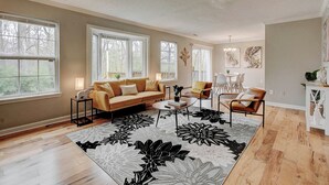 A spacious living room with a beige sofa, a coffee table, and a patterned rug.