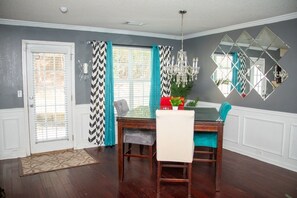 A dining area with a wooden table, chairs, a chandelier, and a decorative mirror on the wall. - 8 min from the airport, located right off exit (college park)