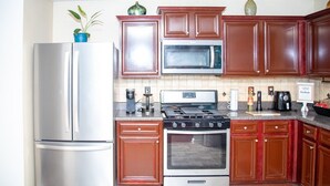 Une cuisine équipée d’appareils électroménagers en acier inoxydable, de meubles en bois et d’un dosseret carrelé.