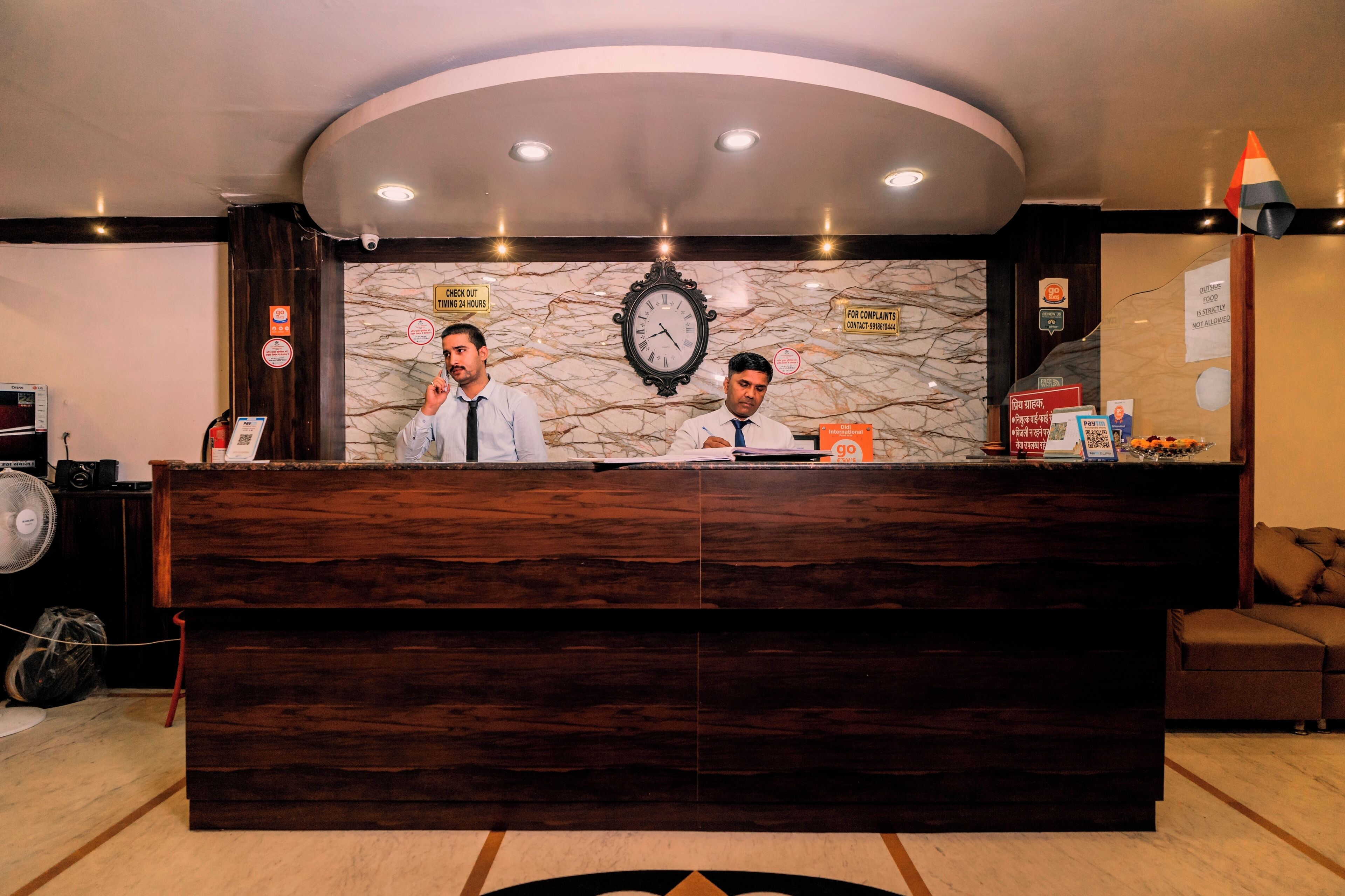 A reception desk with a clock, a sign for complaints, and a fan.