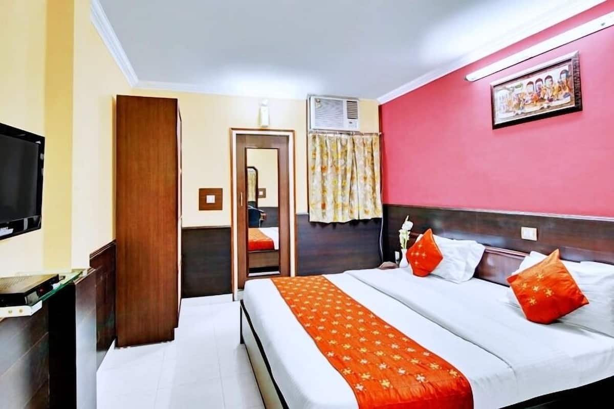 A hotel room with a bed, a television, a desk, and a door leading to a bathroom.