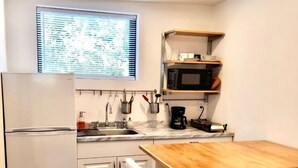 Eine kompakte Küche mit weißen Schränken, einem Holztisch und einem Edelstahl-Kühlschrank.