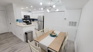 A modern kitchen with white cabinetry, a built-in microwave, and a stainless steel refrigerator.