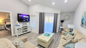 A modern living room with a flat-screen TV, a sofa, a coffee table, and a bookshelf.