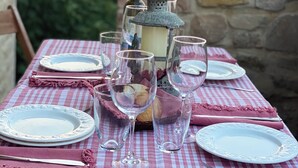 Una mesa preparada para una comida, con mantel a cuadros, copas de vino, platos y un candelabro.