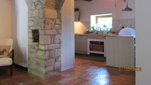 Una cocina rústica con un arco de piedra, techo de madera y ventana con vistas.