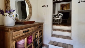 Un aparador de madera con espejo, un florero con flores y una escalera que lleva a un comedor.