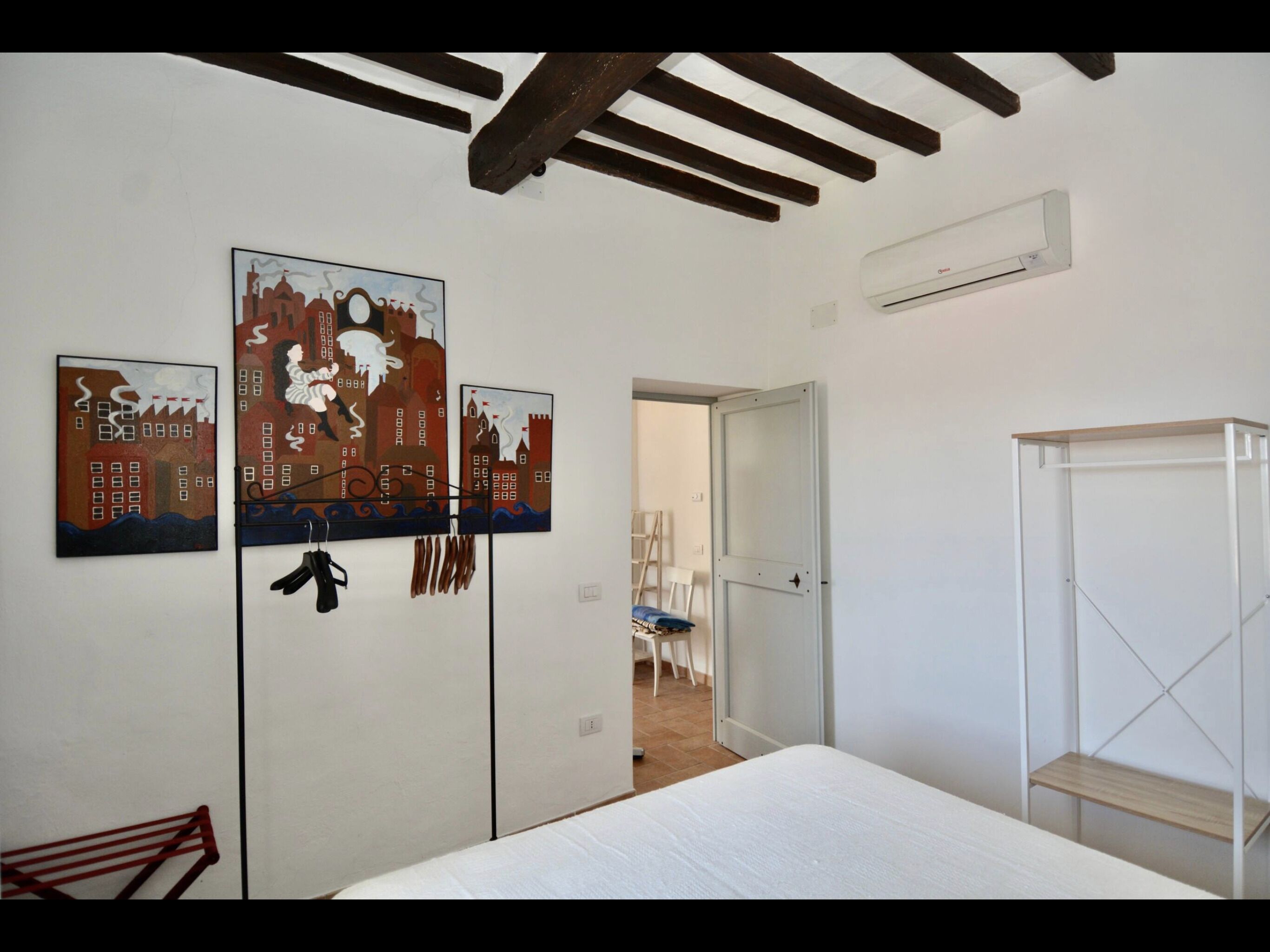 Un dormitorio con cama, armario y dos cuadros en la pared.