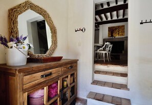 Un aparador de madera con espejo, un florero con flores y una escalera que lleva a un comedor.
