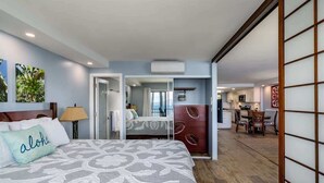 A hotel room with a bed, a desk, a chair, and a view of the kitchen.