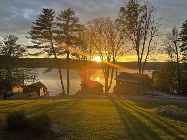 A lakeside property with cabins, a grassy lawn, and trees.