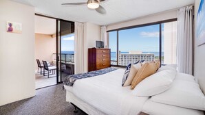 Een hotelkamer met een bed, een televisie, een dressoir en een balkon met uitzicht op zee.