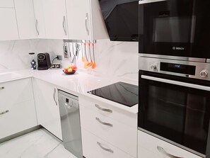 Une cuisine moderne avec des meubles blancs, un four Bosch et un lave-vaisselle.