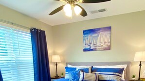 A bedroom with a bed, a ceiling fan, a painting of sailboats, and a window with curtains. - NEW! SPACIOUS condo—STUNNING views & CLOSE to Strip, SDC & LAKE! Sleeps 12!! (Branson)