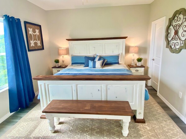 A bedroom with a bed, bedside tables, a bench, and a decorative wall piece.