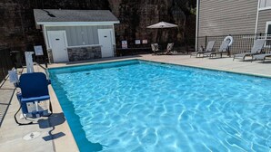 A swimming pool with lounge chairs and a small building, likely a changing room or storage. - NEW! SPACIOUS condo—STUNNING views & CLOSE to Strip, SDC & LAKE! Sleeps 12!! (Branson)