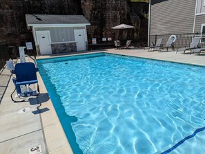 Une piscine avec des chaises longues et un petit bâtiment, probablement un vestiaire ou un local de rangement.