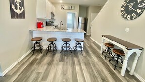 A kitchen with a central island, bar stools, a clock, and a sign that reads "Kitchen". - NEW! SPACIOUS condo—STUNNING views & CLOSE to Strip, SDC & LAKE! Sleeps 12!! (Branson)