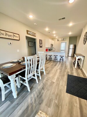 A modern kitchen with white cabinets, a central island, and a stainless steel refrigerator.