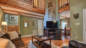 A cozy living room with a fireplace, wooden ceiling, and a television. - DOG FRIENDLY! Less than a mile from Dollywood and a min drive to the Parkway (Pigeon Forge)