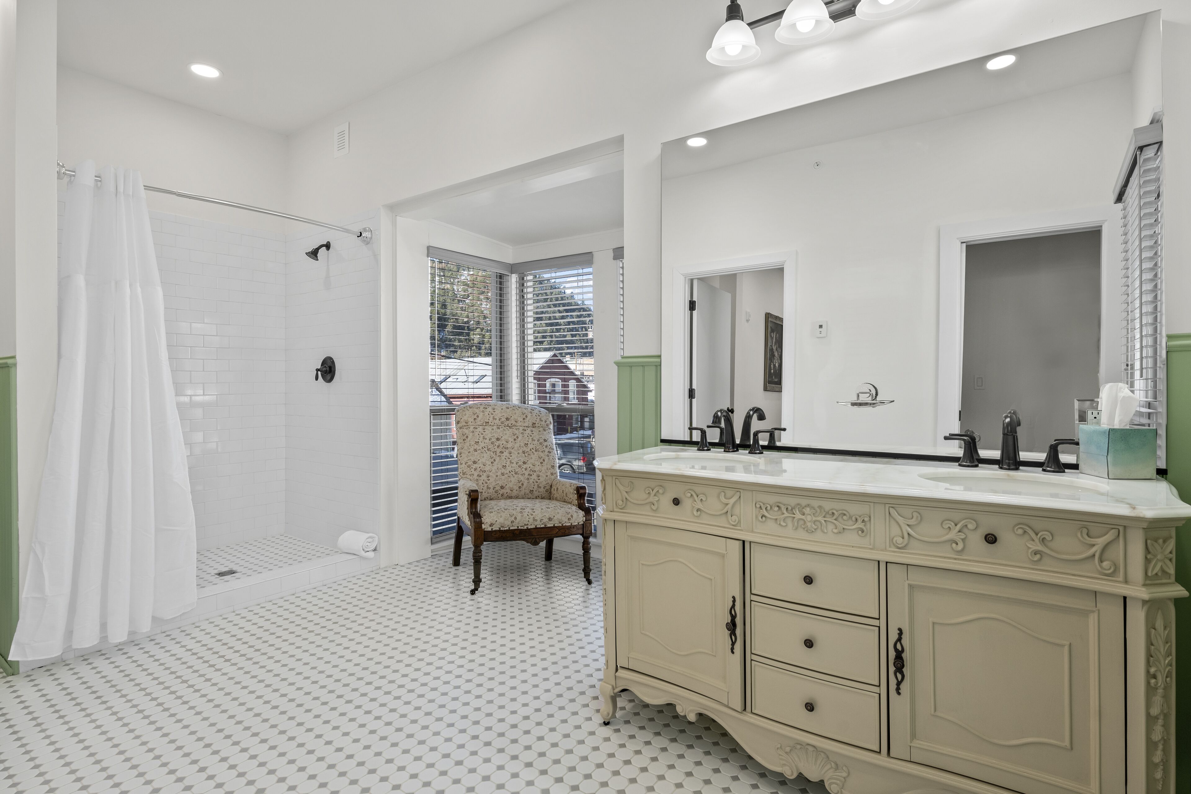 Une salle de bain avec une douche, un meuble-lavabo doté d’un grand miroir et un sol à motifs.