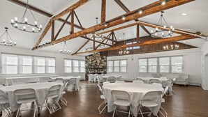 A spacious hall with high ceilings, exposed wooden beams, and multiple round tables with white tablecloths and chairs. - Club Hotel Colorado (Idaho Springs)
