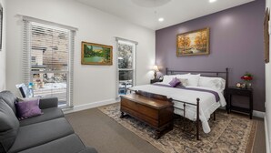 A bedroom with a bed, a dresser, a nightstand, and a window with blinds. - Club Hotel Colorado (Idaho Springs)