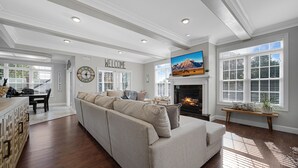 A spacious living room with a large beige sectional sofa, a fireplace, and a television mounted above it.