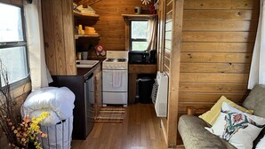 Une cuisine compacte avec des murs en bois, une cuisinière, un four à micro-ondes et un évier.